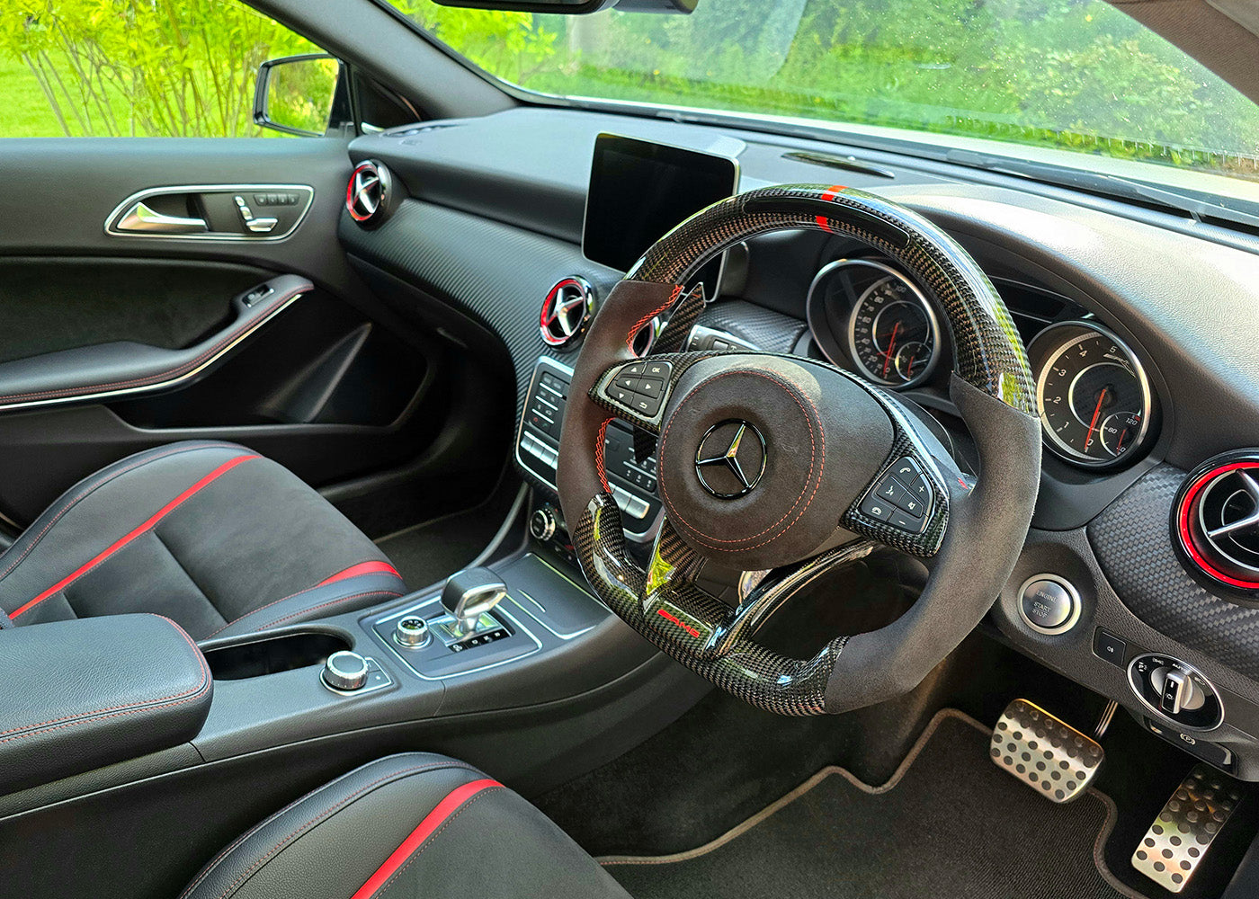 Custom carbon fibre Mercedes AMG-style steering wheel with LED shift lights and magnetic paddles installed in A45 interior