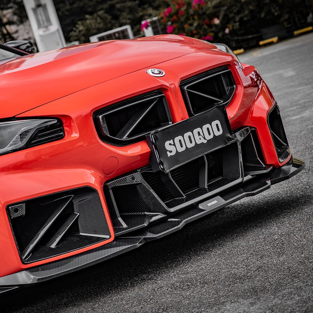 SOOQOO carbon fibre Front Splitter V2 installed on BMW M2 (G87), front three-quarter view on orange car